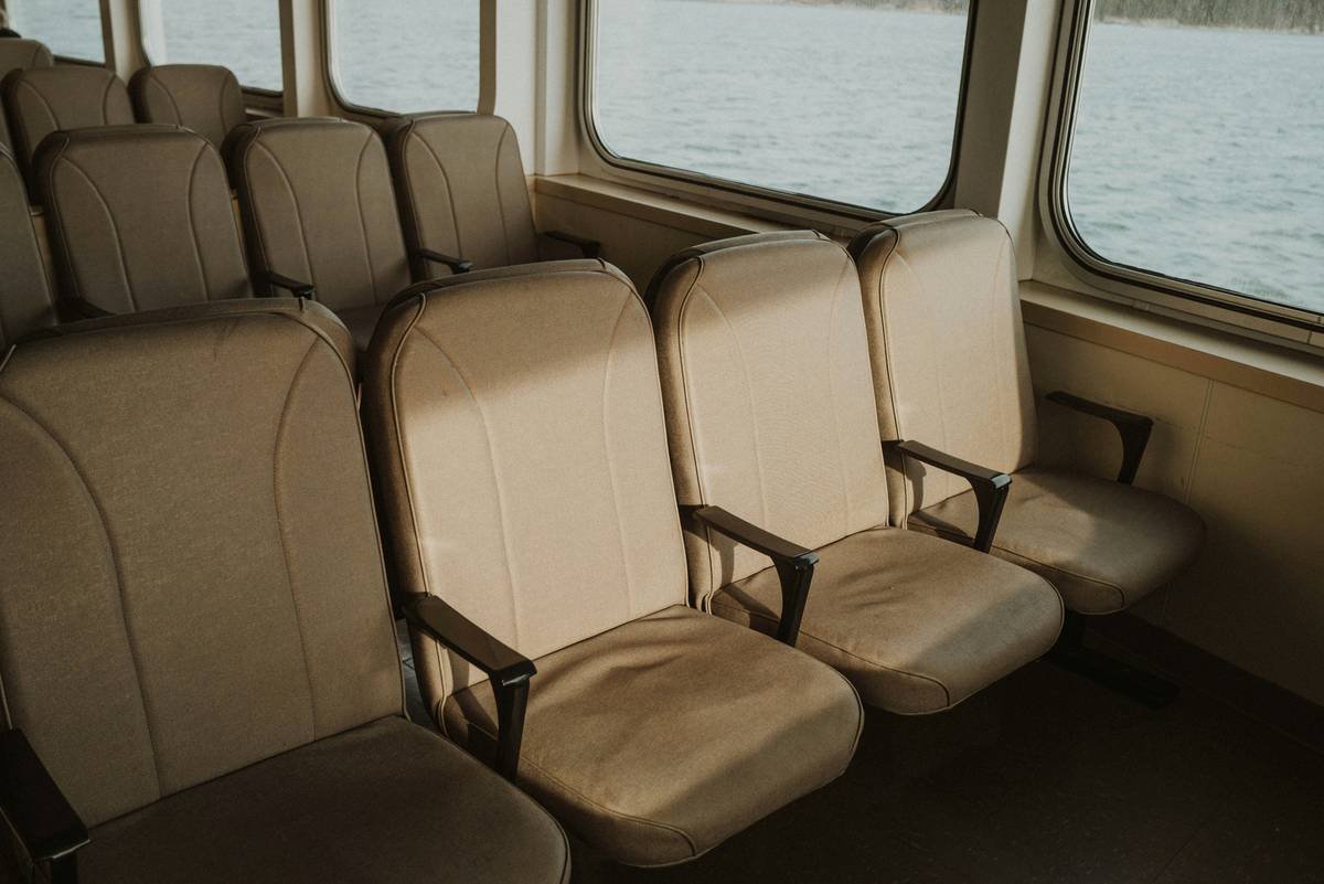 Empty seats on a boat near the window.