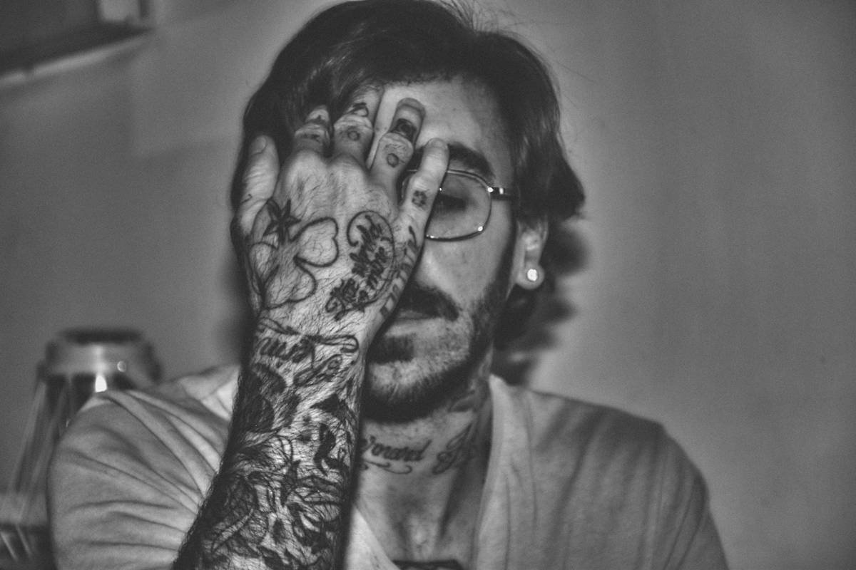 Man with tattoos covering his face and arm.