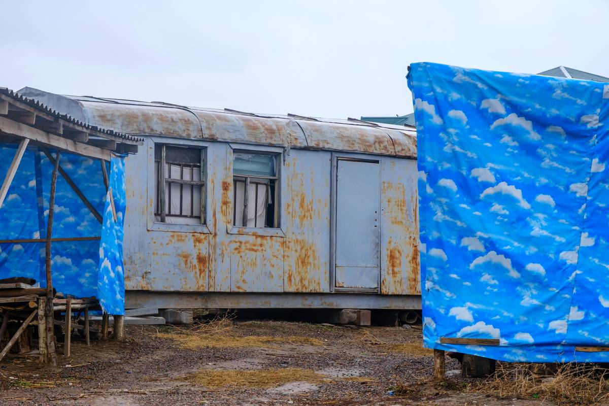 An old, rusty trailer surrounded by blue tarps